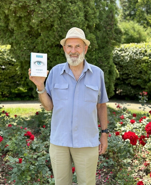 Natural Pharmaceuticals Vistan Šypsantis senjoras laiko pakuotę su Vistan akių sveikatos papildais gėlių fone parke.